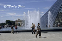 Fountain near the glass pyramid entrance to the Louvre.  In the background is the Petit Arc de Triomphe, Paris, France