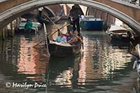 Gondola, gondolier, and a low bridge, Venice, Italy