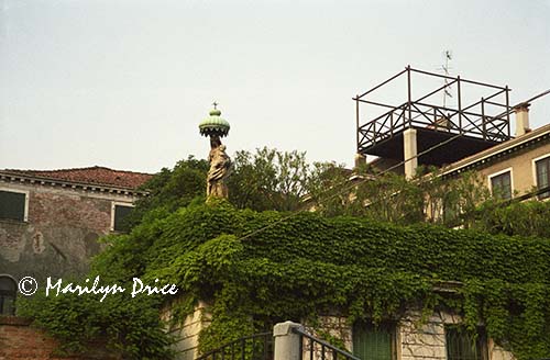 Statue atop a wall around a private garden, Venice, Italy