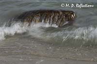 Waves crash over an embedded rock