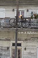 Bicycle lashed to a second store balcony with its basket used as a planter, Key West, FL